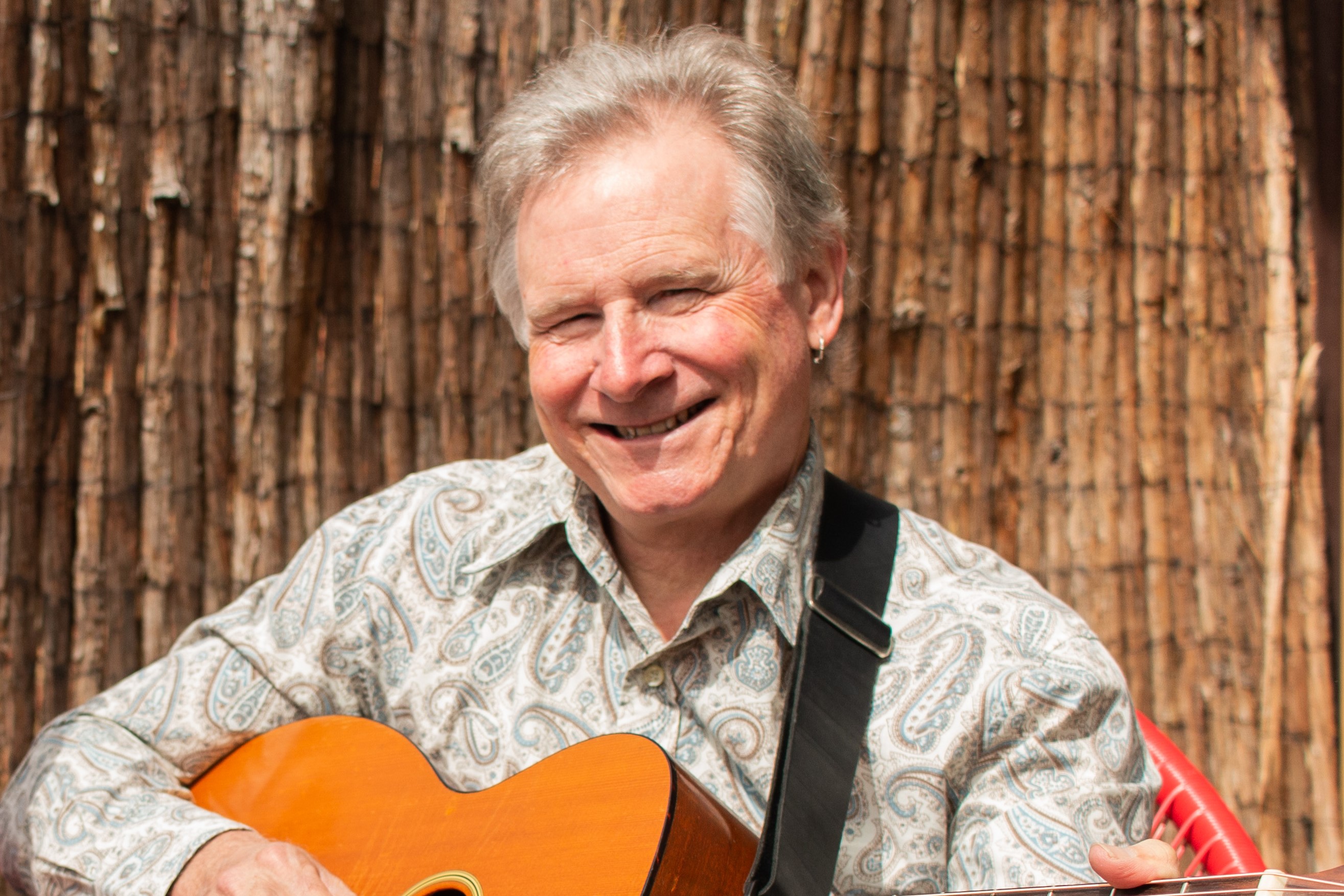 Peter Hicks Photo of Peter Hicks smiling holding a guitar